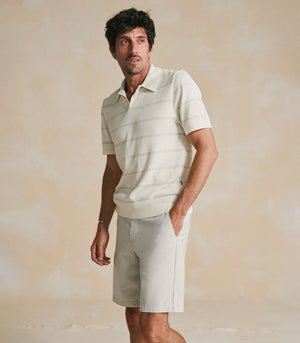 Man wearing a light-colored polo shirt and shorts against a beige background